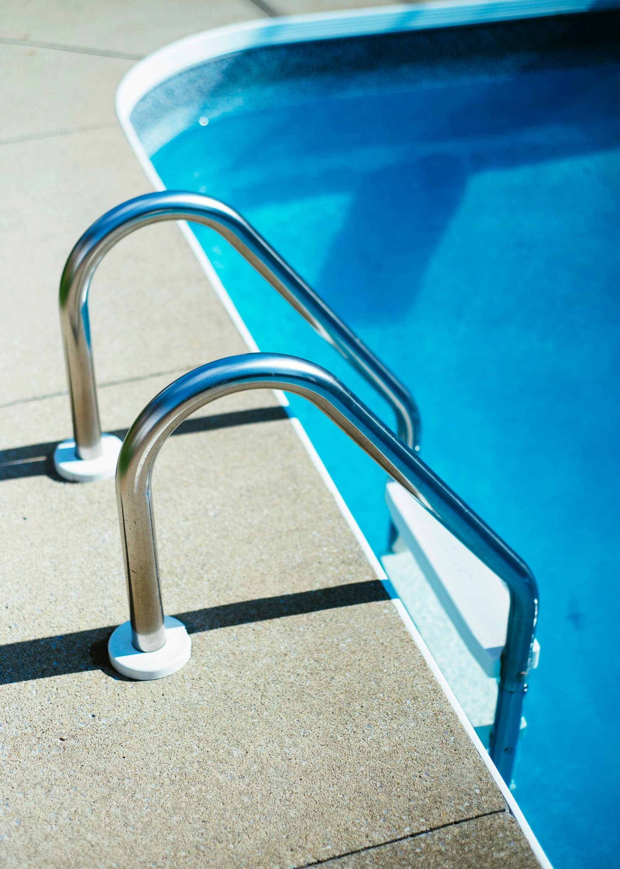 Stainless steel pool ladder over bright blue water